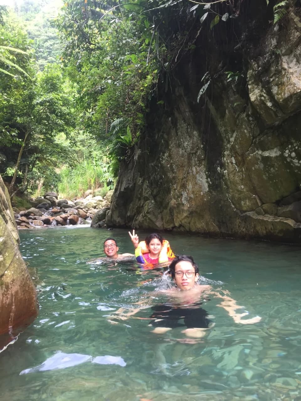 Grup gathering dokter berfoto bersama dengan spanduk di tengah sungai yang jernih.