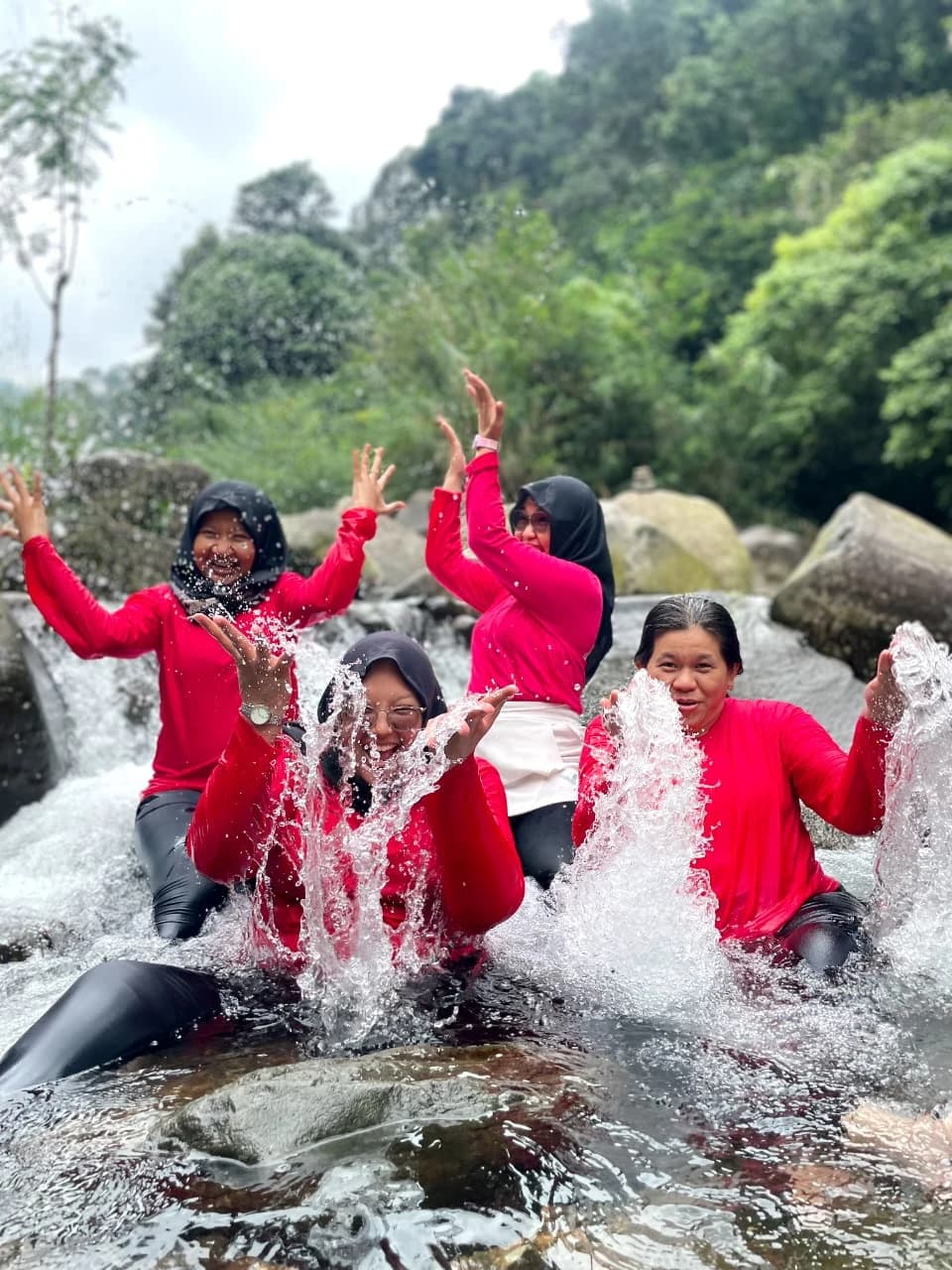 Foto bersama rombongan ibu-ibu berseragam pink di area parkir dengan latar langit biru.