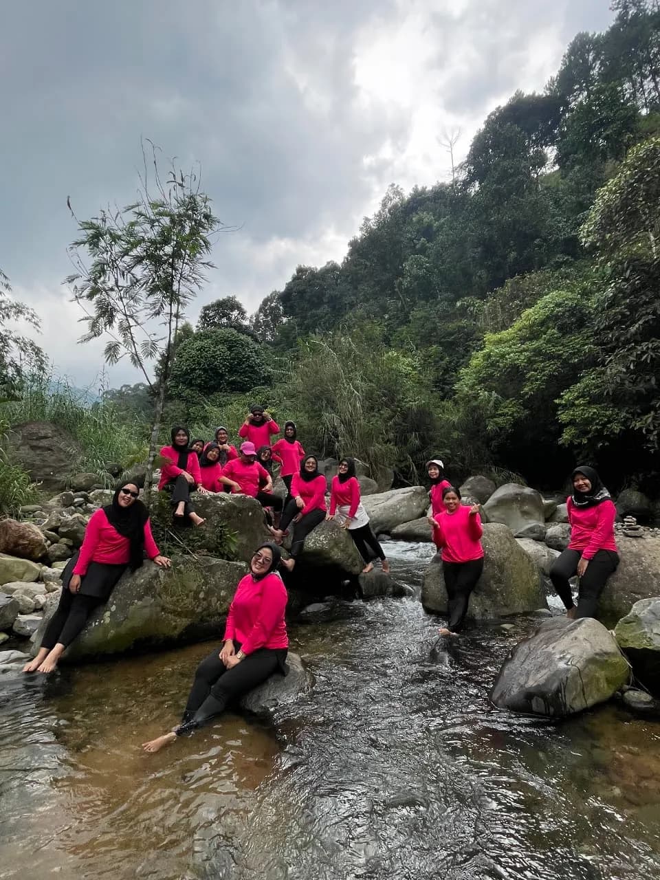 Para peserta beristirahat dan berfoto di atas bebatuan besar di tepi sungai.