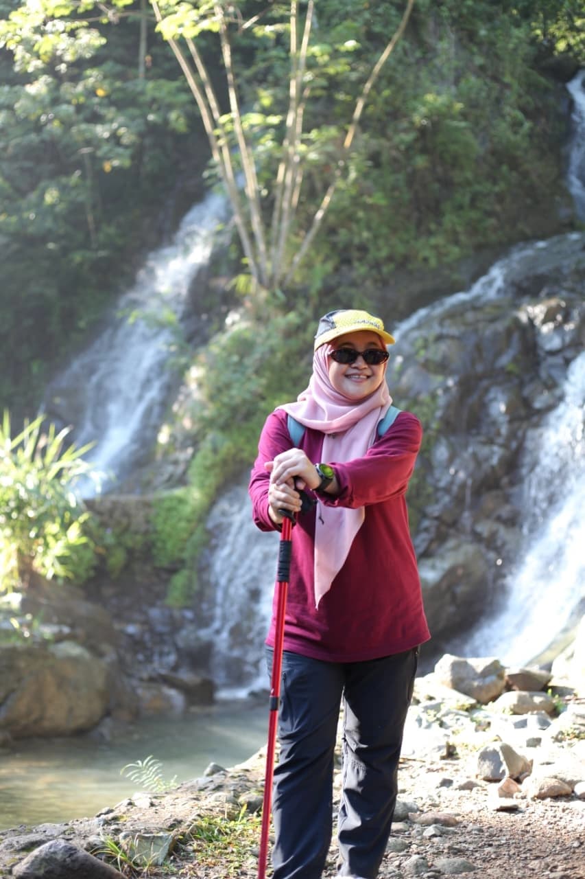 Foto bersama seluruh peserta outing perusahaan di lapangan hijau dengan spanduk.
